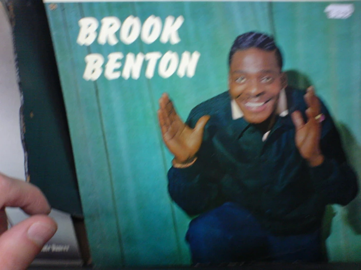 a man holds up a book on a shelf