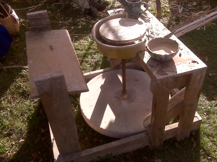 a stone grinder with an old fashioned bowl and metal pan