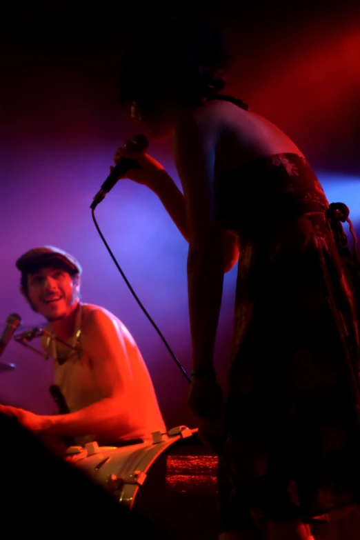 a woman in a dress and hat is standing at a microphone