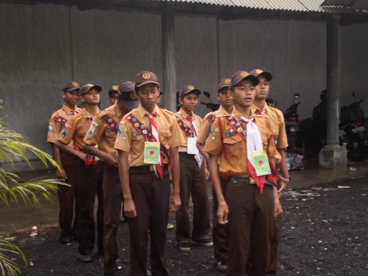 many people stand wearing brown uniforms and are smiling