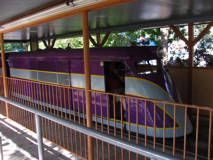 a purple train that is sitting next to a walkway