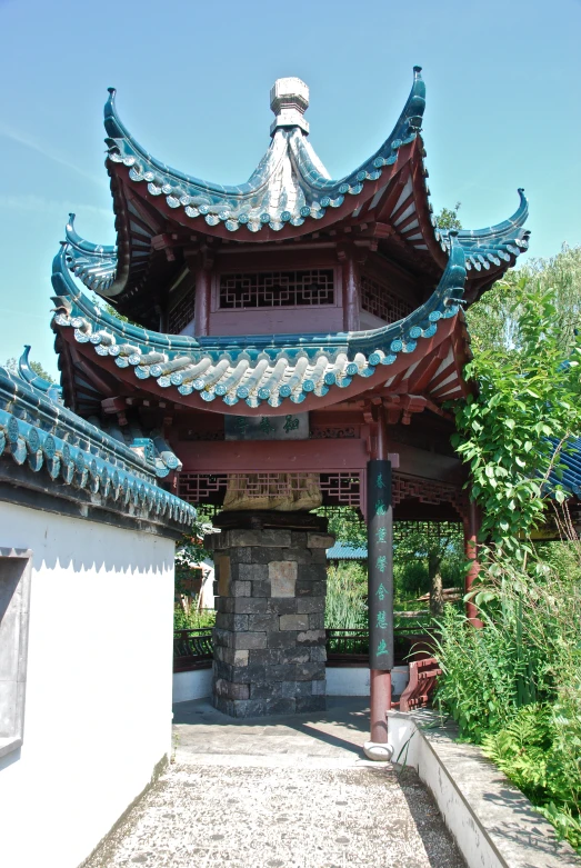 a small asian building surrounded by green trees