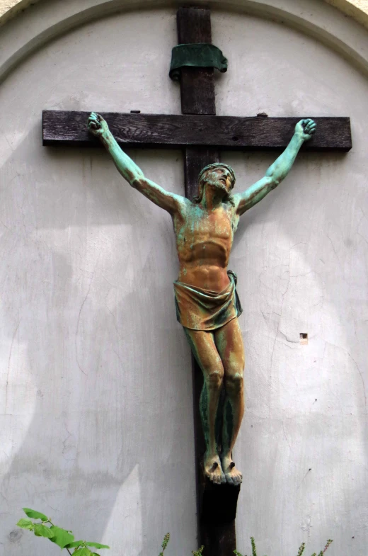a statue is standing on a wooden cross