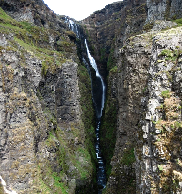 a large waterfall in the middle of some very tall mountains