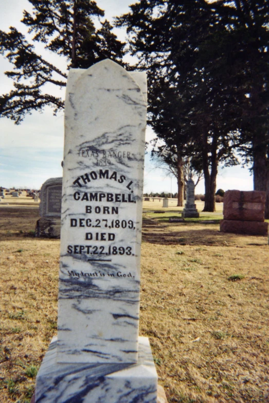 a grave in a cemetery sitting in the grass