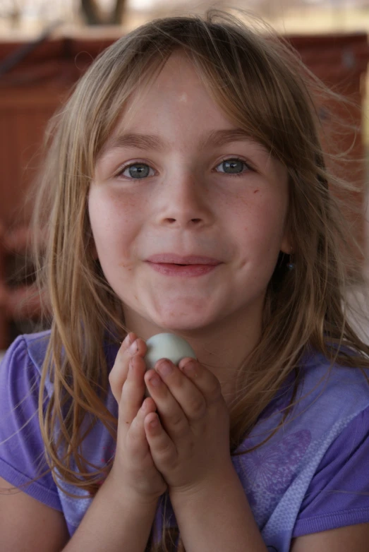 a girl in blue shirt holding soing in her hand