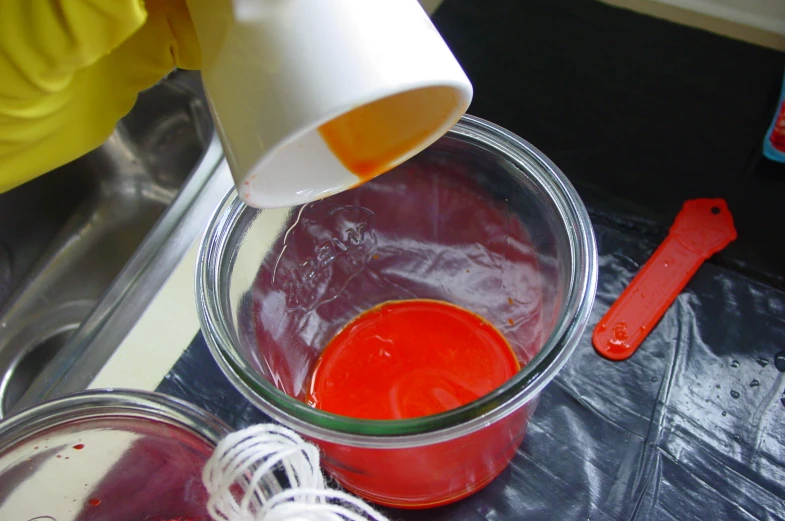 a person mixing liquid in a container with plastic wrap