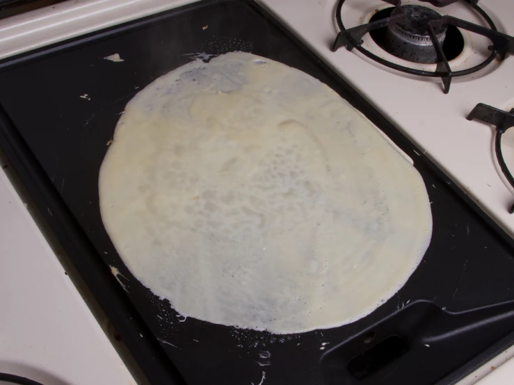 a round of dough being prepared on an electric stove top