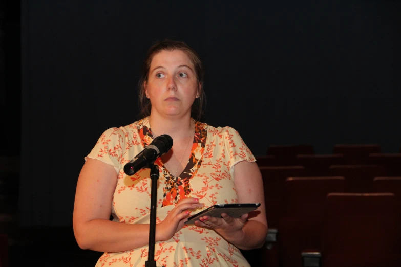 a woman standing in front of a microphone next to an electronic device