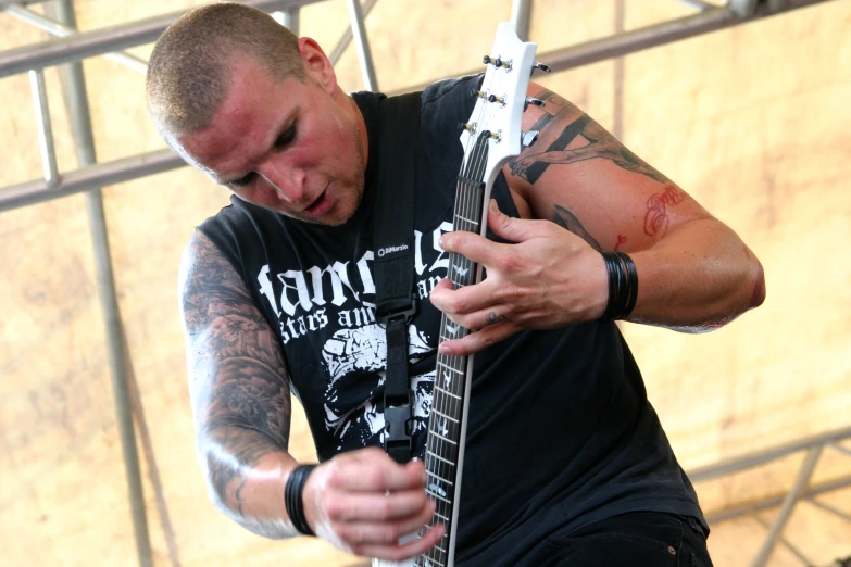a man with an evil tattoo holding onto a guitar