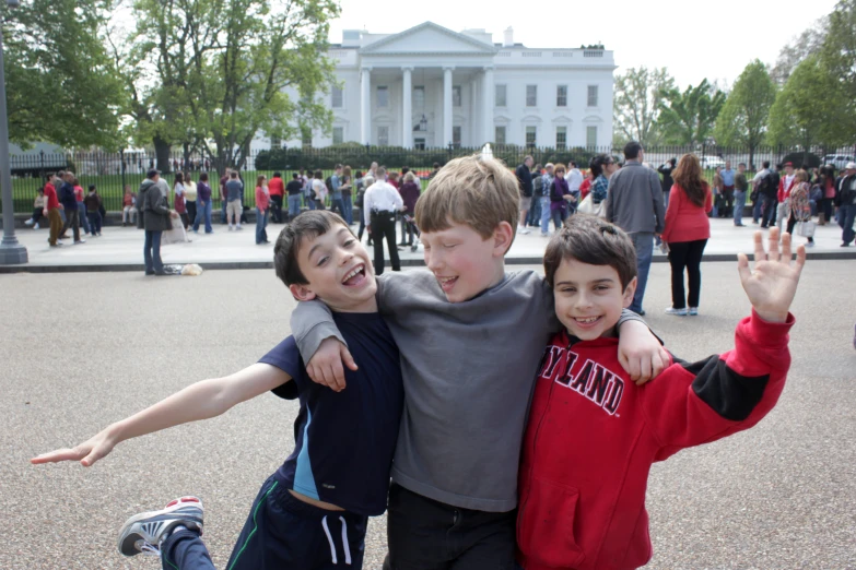 two boys and a girl standing in front of the white house