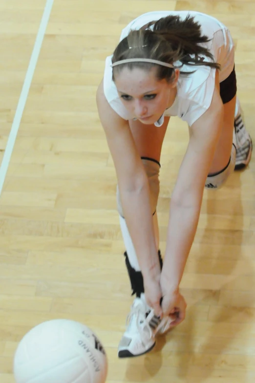 a girl is reaching down for a ball on the court