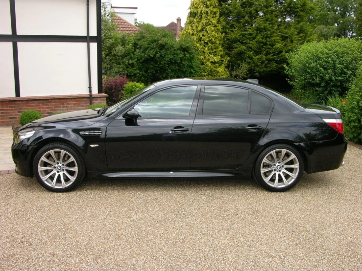 black bmw s6 in driveway next to bushes