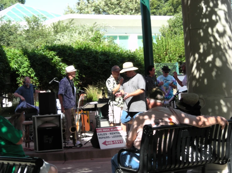 a band playing in a shady spot by trees