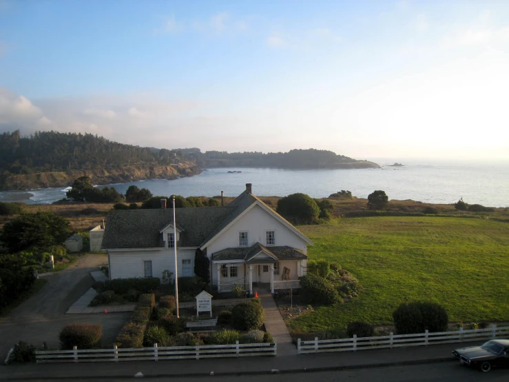 a house is located in a small yard and overlooks a large body of water