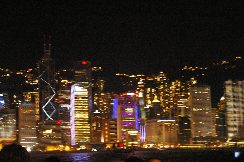 night view of a city with skyscrs, and a boat in the ocean