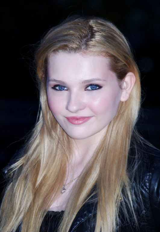 a woman with long blonde hair and blue eyes posing for the camera