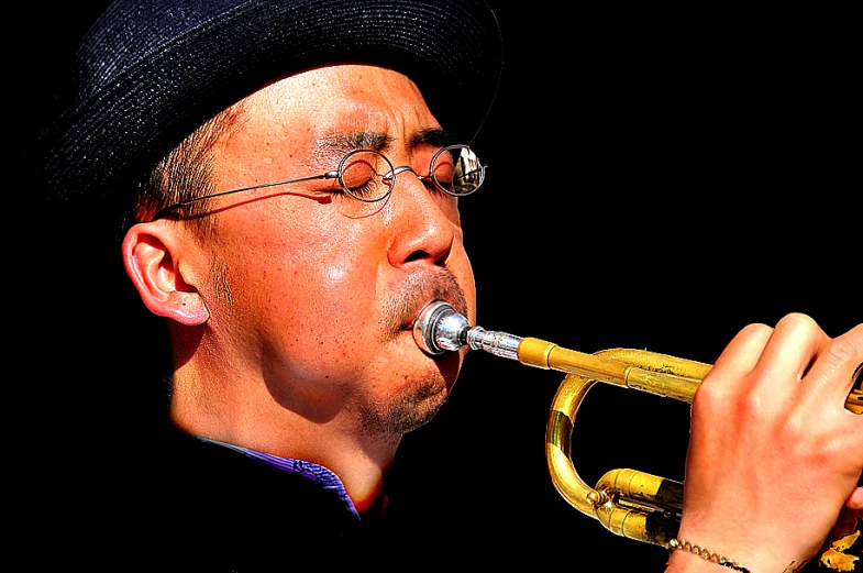 a man in black hat playing trumpet on stage