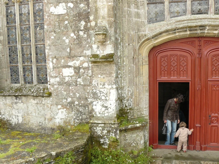 a man and child stand outside a red door