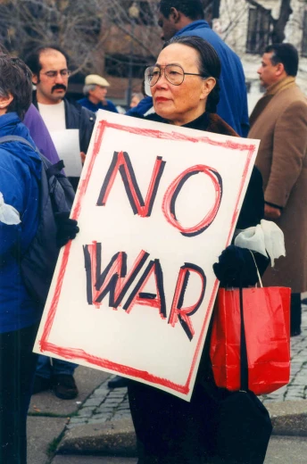 a woman with glasses holds up a sign