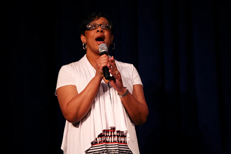 a woman wearing glasses is holding a microphone