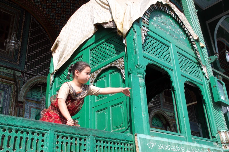 woman pointing at the balcony railing of green painted building