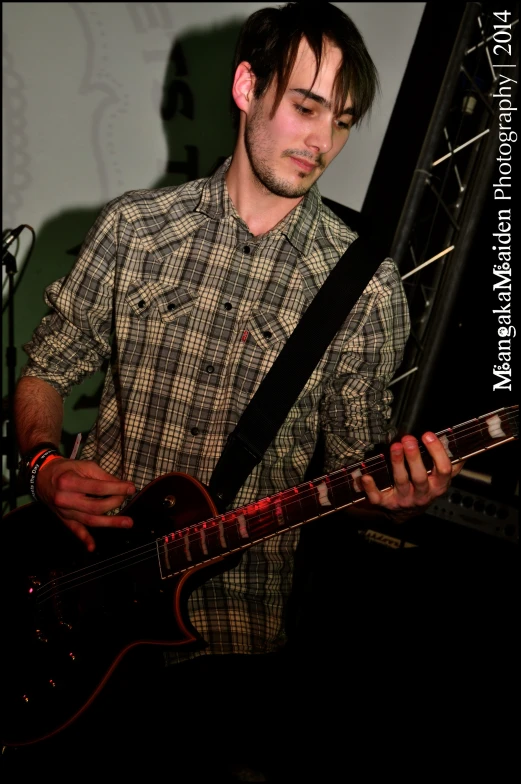 a man standing on stage with a guitar and wearing a tie