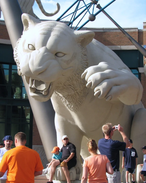 several people sitting next to a giant white lion statue