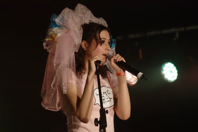 a woman standing next to a microphone with a veil on her head