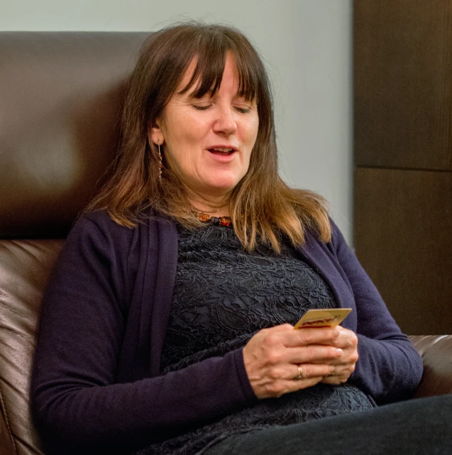 a woman sitting on a leather couch looking at her phone