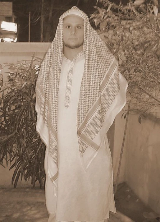 a man in white is standing by a plant