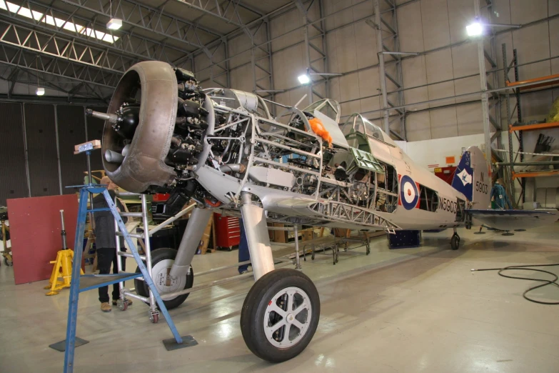 a silver airplane with multiple engine wheels sitting in a hanger
