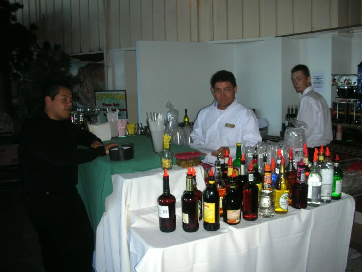several men are at a table with bottles of wine and liquor