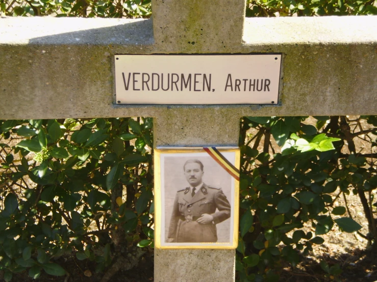 a cross is on the grass next to a plaque