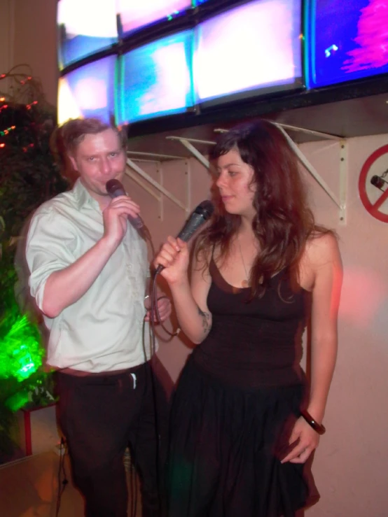 a man and a woman talking into microphones while standing next to each other