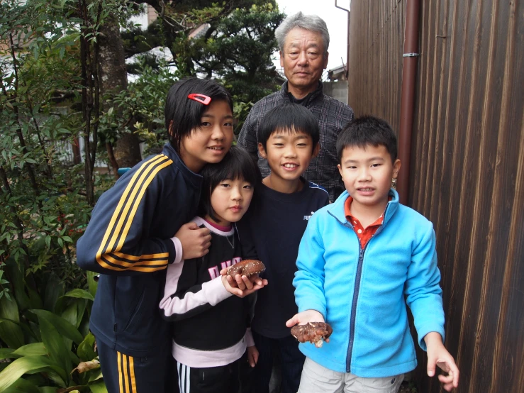 five people stand in front of a wall and one person is holding a donut