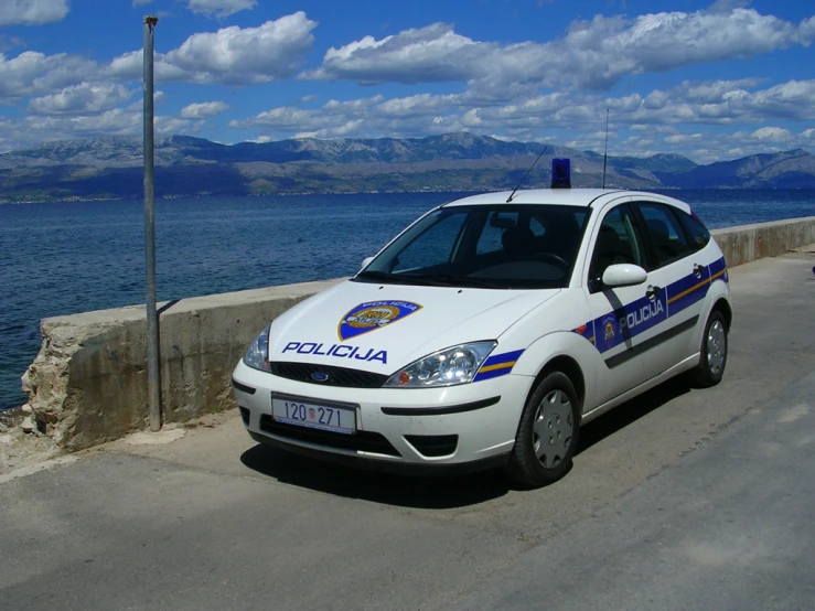 a police car driving on a road by water