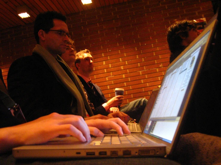 three people sitting around a laptop looking at the screen