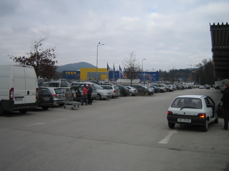 a parking lot with parked cars and several people