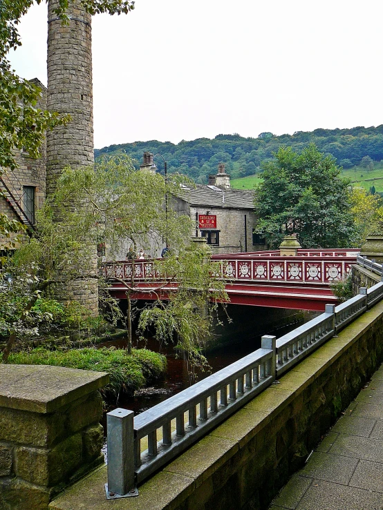 a bridge spanning across a small stream near an old building