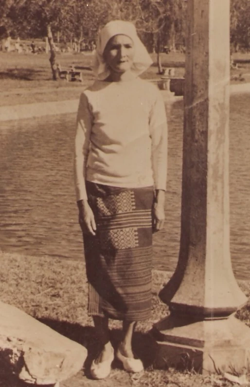 a person standing near a pillar with a hat on