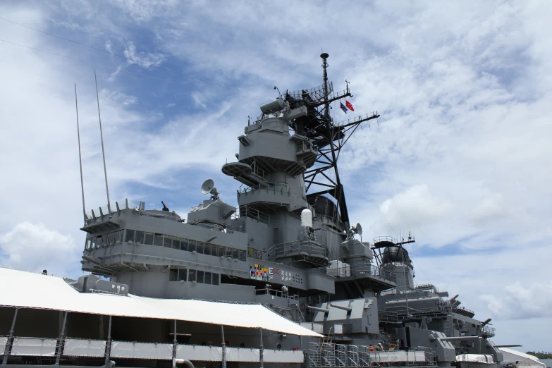 a large military ship sitting under a blue cloudy sky