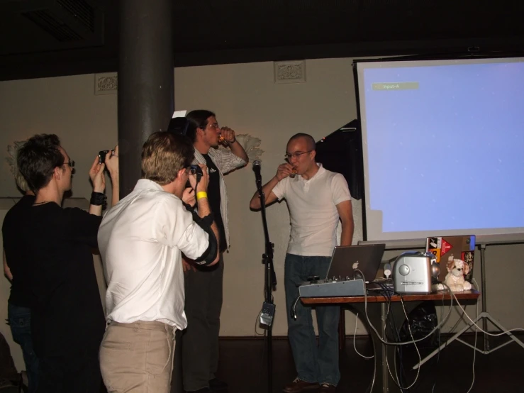 several people standing in front of a large screen