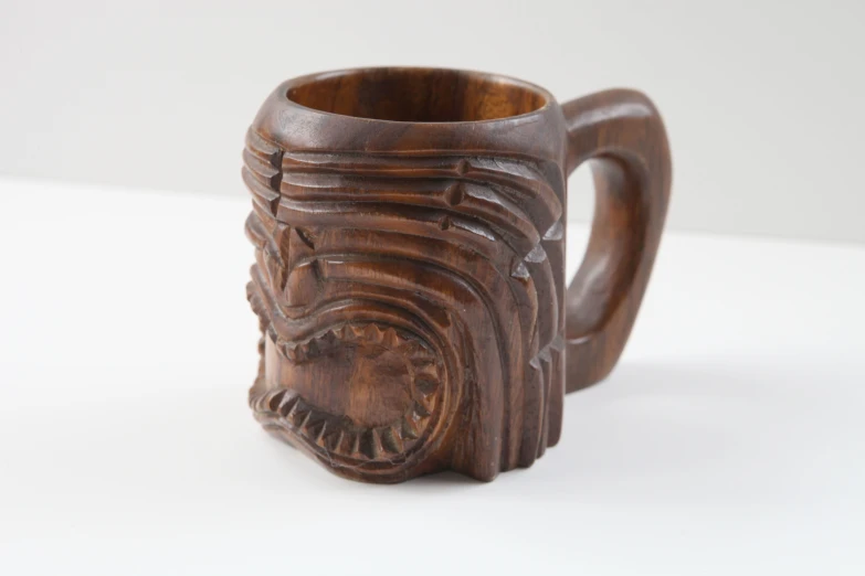 an intricate carved wooden mug on a white background