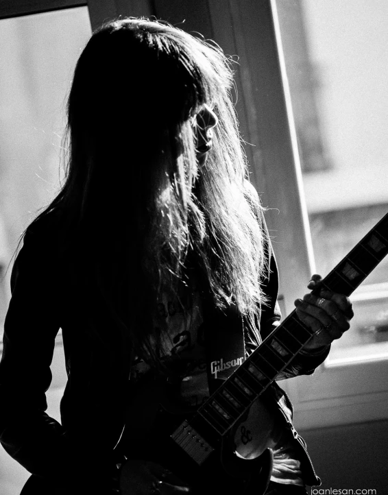 a woman with long hair is playing an electric guitar