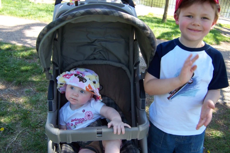 the two children are in the stroller giving the peace sign