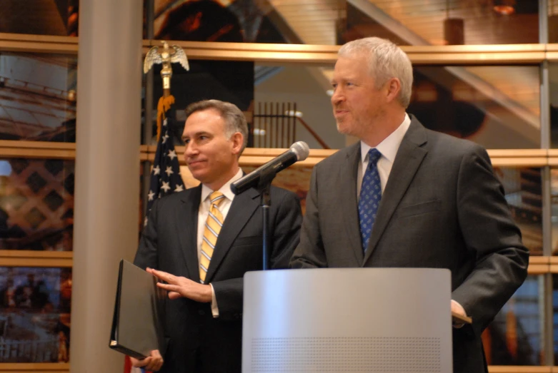 two men standing next to each other near a microphone