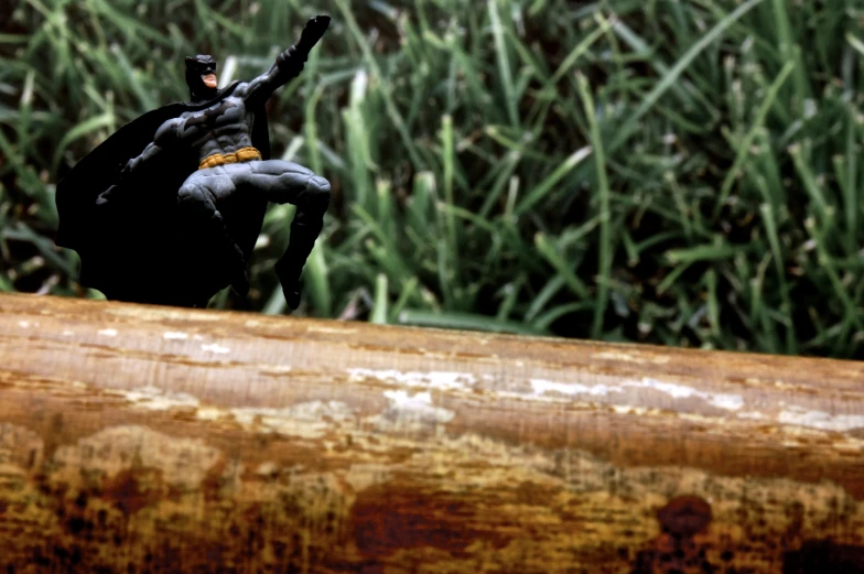 a small toy figure is sitting on a tree log