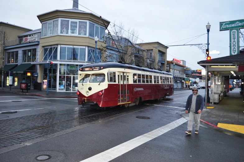 a red and white trolley is going down a street