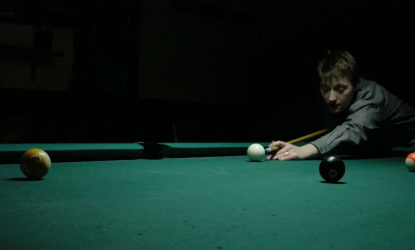 person leaning over to hit bill ball in a game of pool